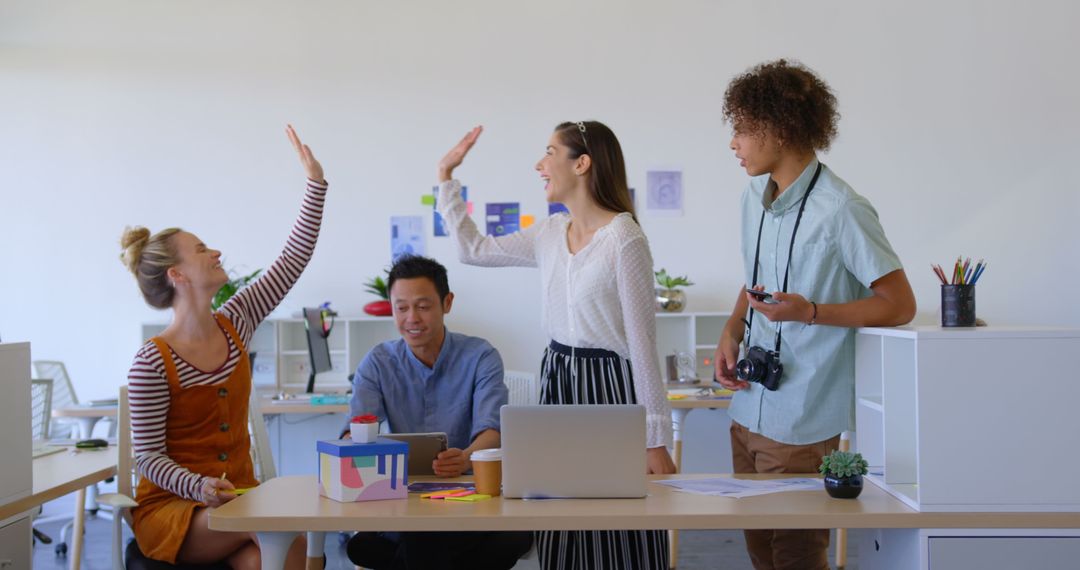 Diverse Team Celebrating Success with High-Five in Creative Office