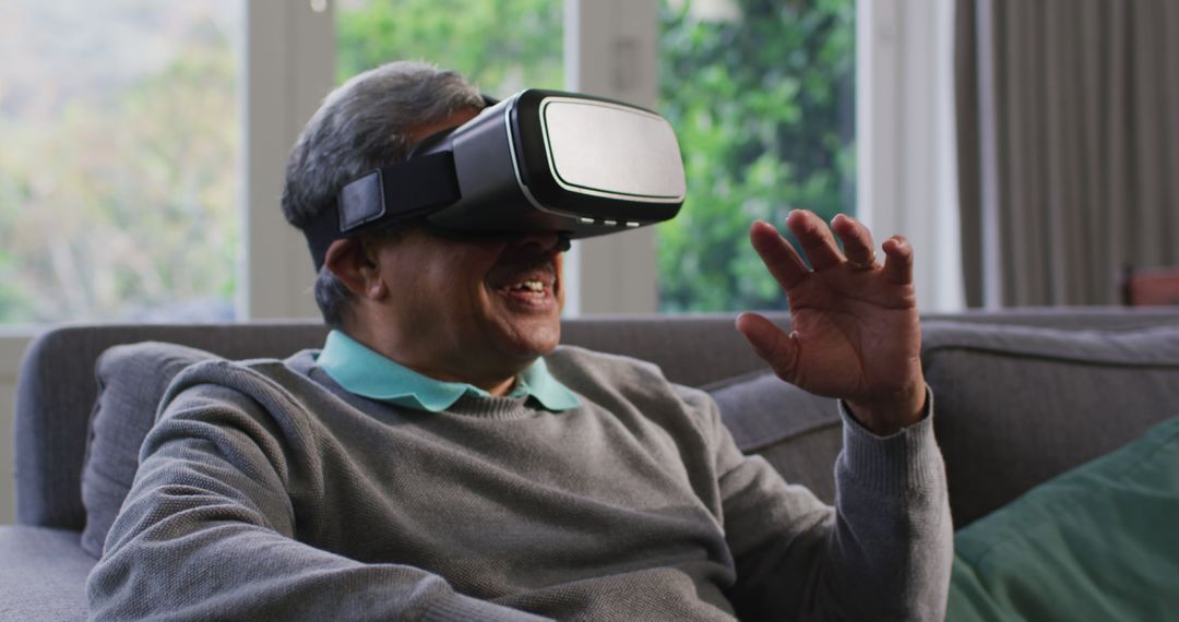 Senior Man Using Virtual Reality Headset Sitting on Sofa - Free Images, Stock Photos and Pictures on Pikwizard.com