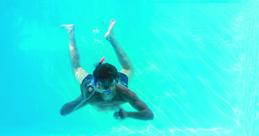 Man Snorkeling Underwater in clear blue pool during vacation