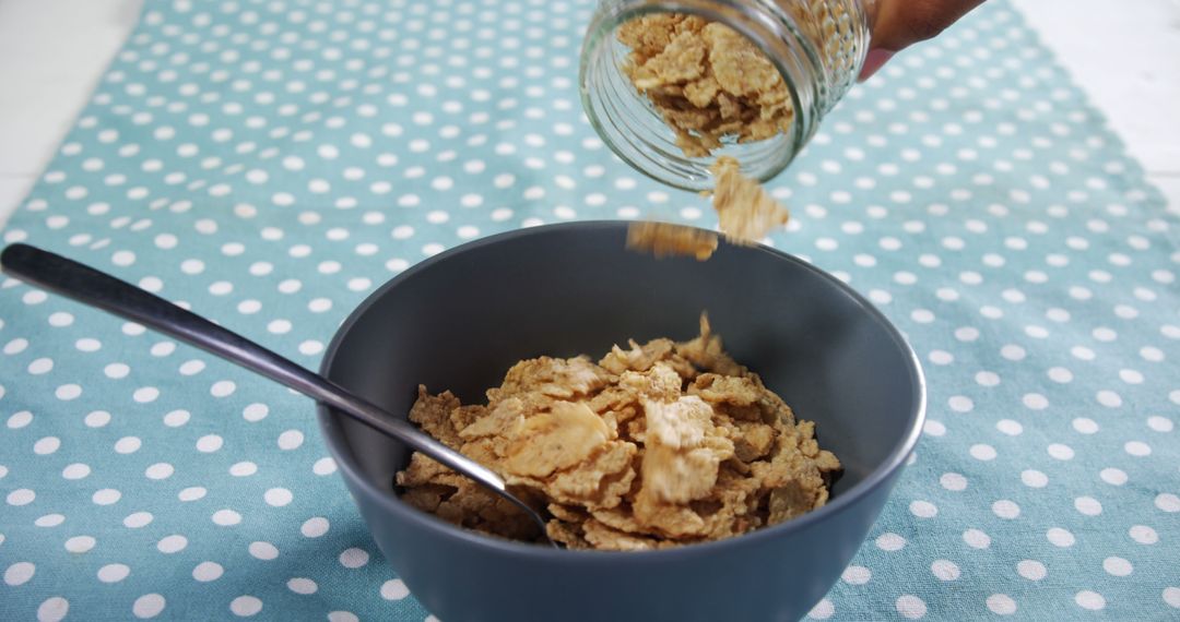 Pouring Breakfast Cereal into Bowl on Polka Dot Tablecloth - Free Images, Stock Photos and Pictures on Pikwizard.com