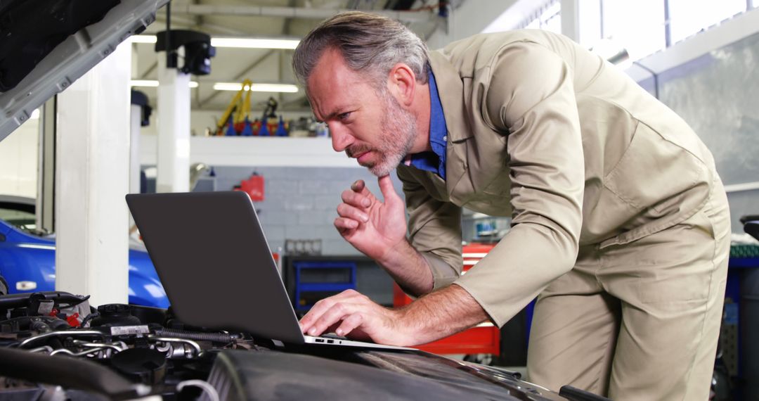 Experienced mechanic diagnosing car engine using laptop - Free Images, Stock Photos and Pictures on Pikwizard.com