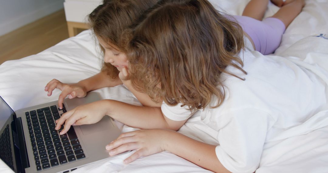 Two Children Using Laptop on Bed at Home Together - Free Images, Stock Photos and Pictures on Pikwizard.com