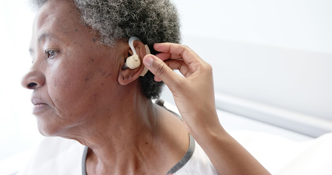 Elderly Woman Receiving Hearing Aid Assistance in Medical Setting - Free Images, Stock Photos and Pictures on Pikwizard.com