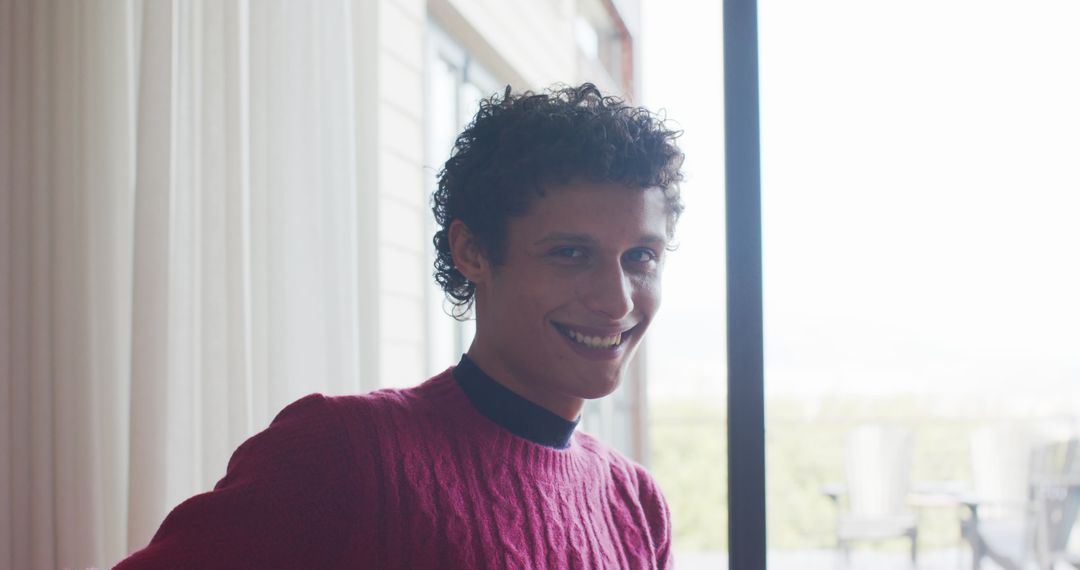 Smiling Young Man Looking Out Window in Modern Home Interior