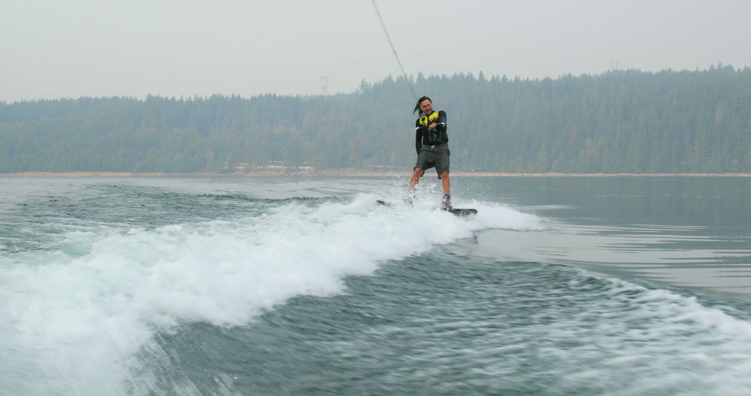 Man Wakeboarding on Calm Lake with Forest Background - Free Images, Stock Photos and Pictures on Pikwizard.com