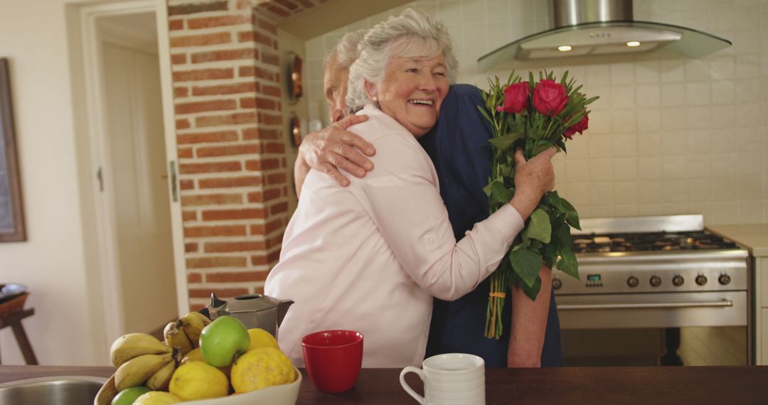 Elderly woman receives flowers in kitchen, expressing joy and gratitude - Free Images, Stock Photos and Pictures on Pikwizard.com