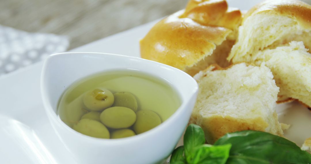 Fresh bread with green olives and basil on white plate - Free Images, Stock Photos and Pictures on Pikwizard.com