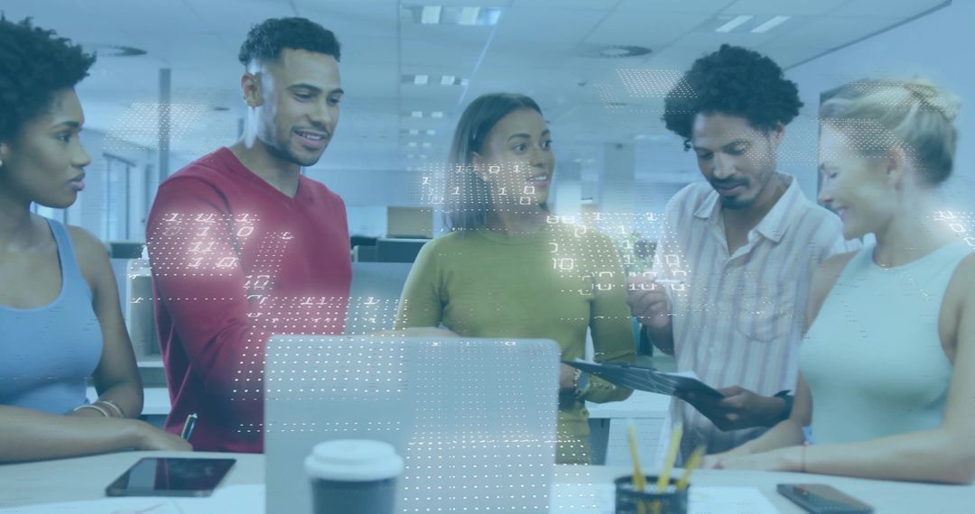 Diverse team collaborating over laptop and tablet in modern open-plan office