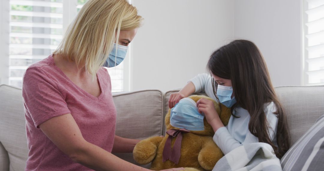 Mother and daughter wearing masks at home with toy bear - Free Images, Stock Photos and Pictures on Pikwizard.com