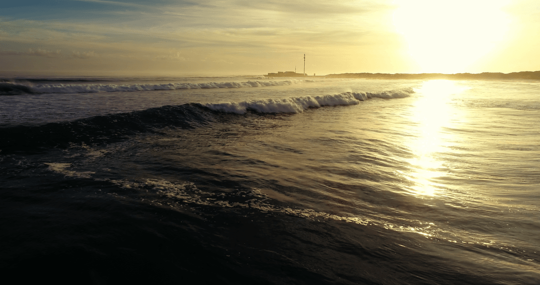 Transparent waves of ocean shine under golden sunset glow