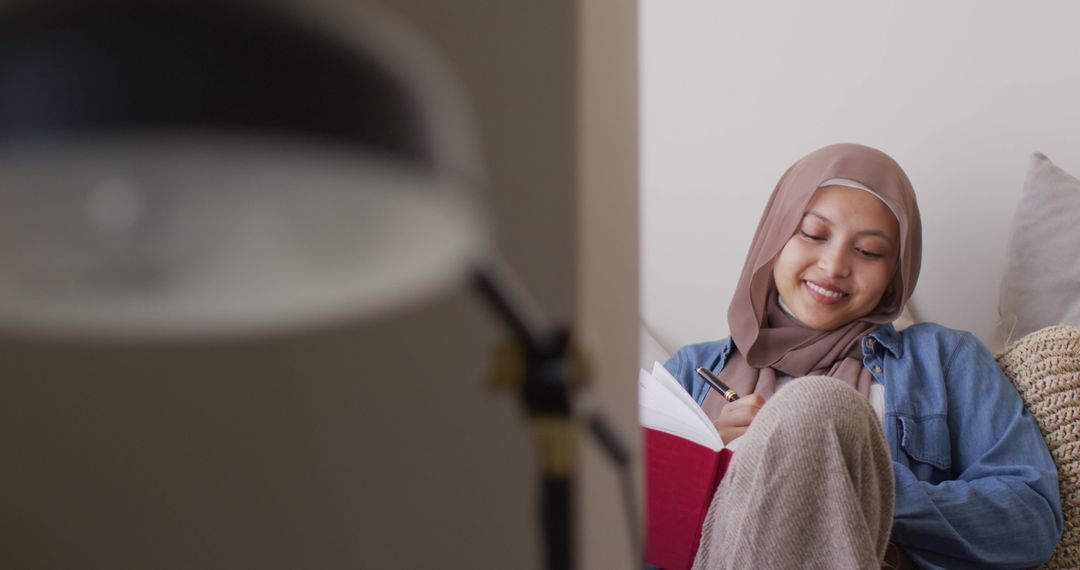 Young Muslim Woman in Hijab Studying and Smiling at Home - Free Images, Stock Photos and Pictures on Pikwizard.com