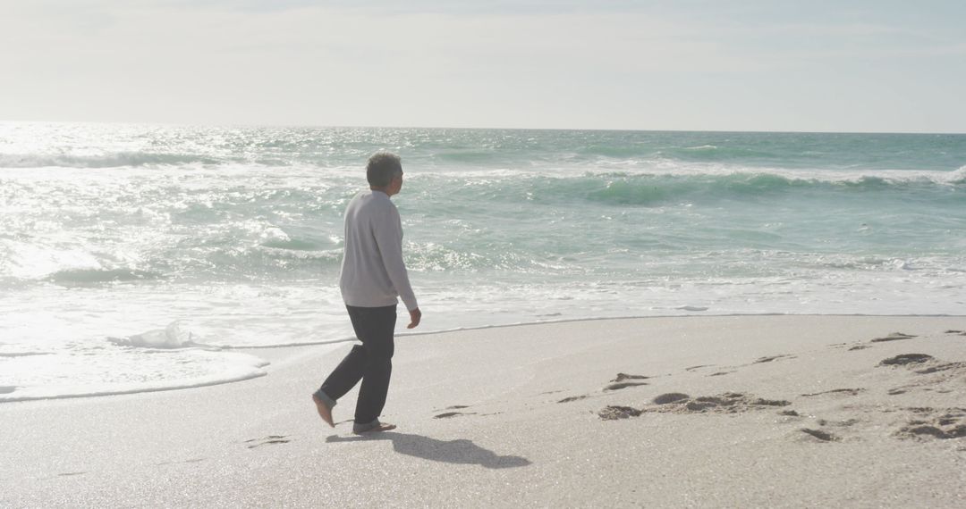 Senior Man Enjoying Peaceful Walk on Beach at Sunset