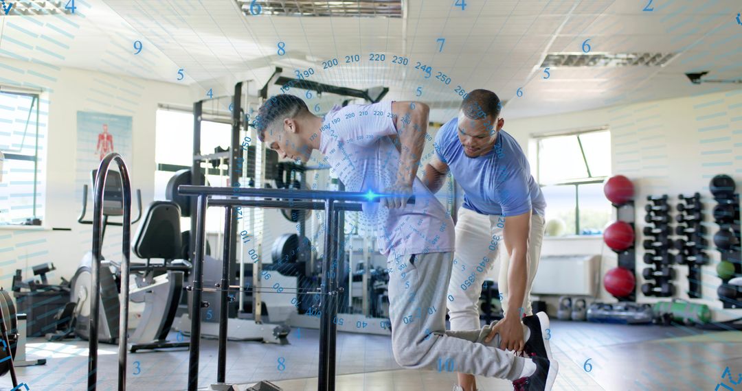 Trainer Assisting Male Client Performing Parallel Bar Dips for Strength Training