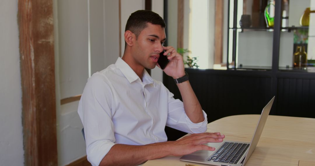 Young Professional Multitasking with Phone and Laptop in Modern Office