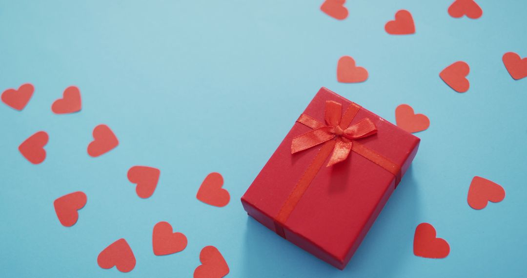 Valentine's Day Gift Box with Scattered Paper Hearts on Blue