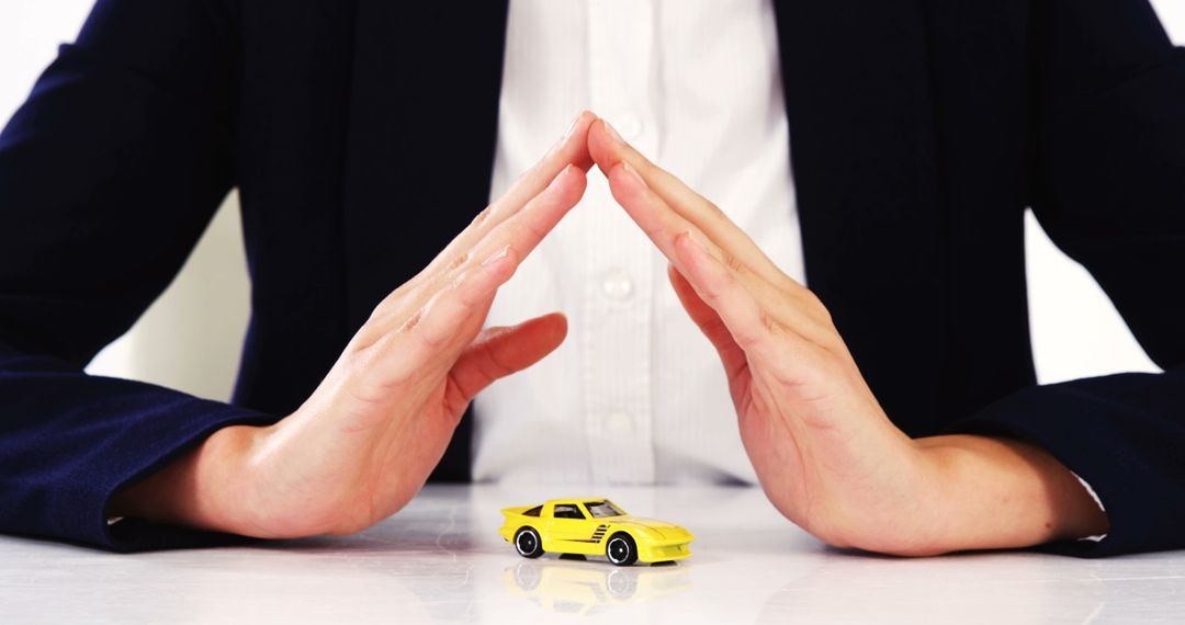 Businessperson Protecting Yellow Toy Car with Hands on White Background - Free Images, Stock Photos and Pictures on Pikwizard.com