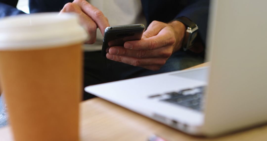 Close-Up of Man Using Smartphone Next to Coffee and Laptop - Free Images, Stock Photos and Pictures on Pikwizard.com