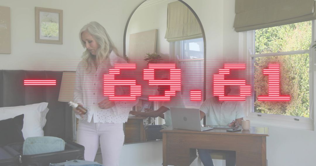 Couple juggling remote work and packing with red -69.61 overlay in bedroom with mirror