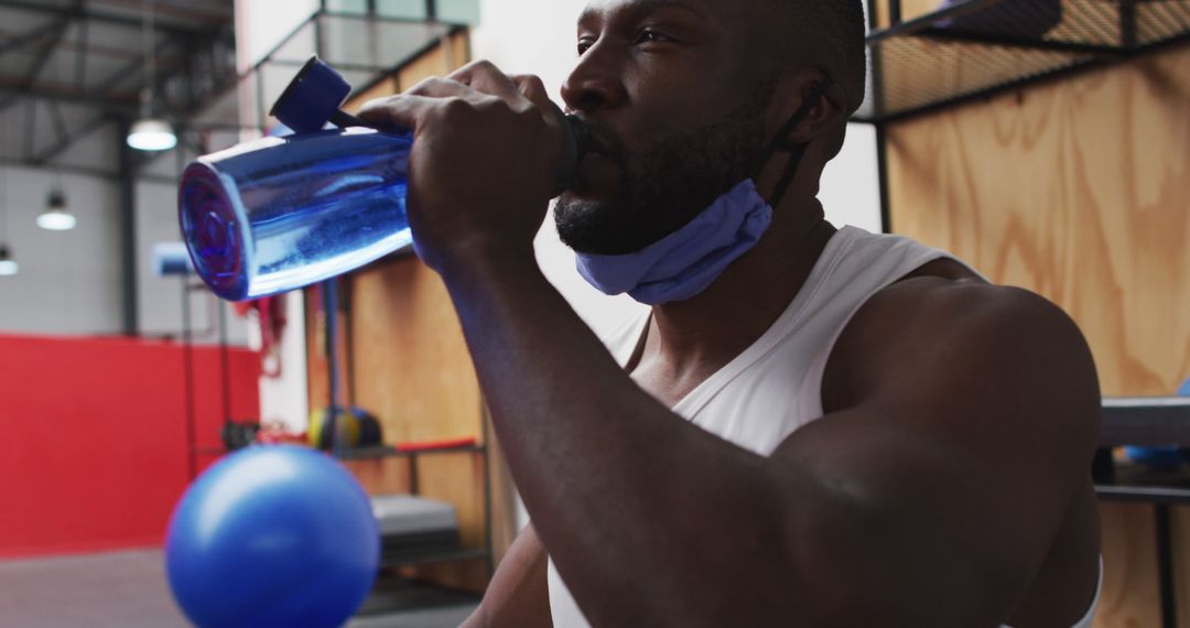 Man Drinking Water during Gym Workout with Blue Ball in Background - Free Images, Stock Photos and Pictures on Pikwizard.com