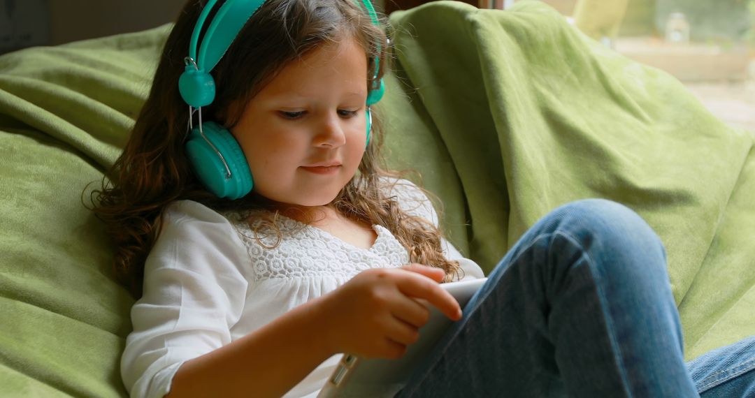 Young Girl Relaxing with Headphones and Digital Tablet on Sofa - Free Images, Stock Photos and Pictures on Pikwizard.com