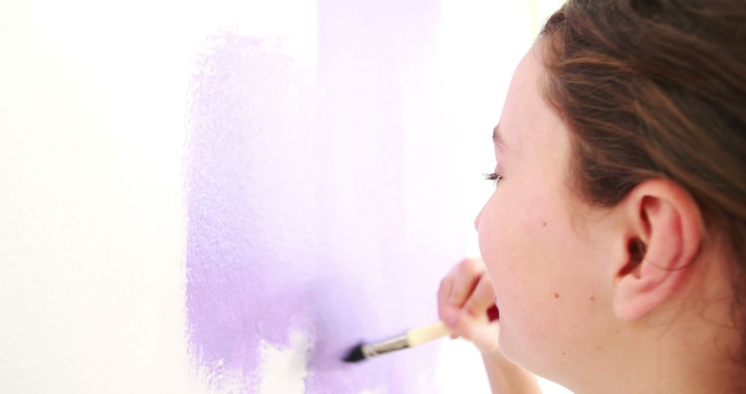 Young girl painting wall with purple color close-up - Free Images, Stock Photos and Pictures on Pikwizard.com