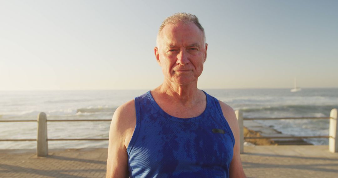 Senior man in blue tank top enjoying a coastal jog - Free Images, Stock Photos and Pictures on Pikwizard.com