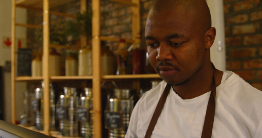 Attentive Male Staff Engaged with Computer at Grocery Counter