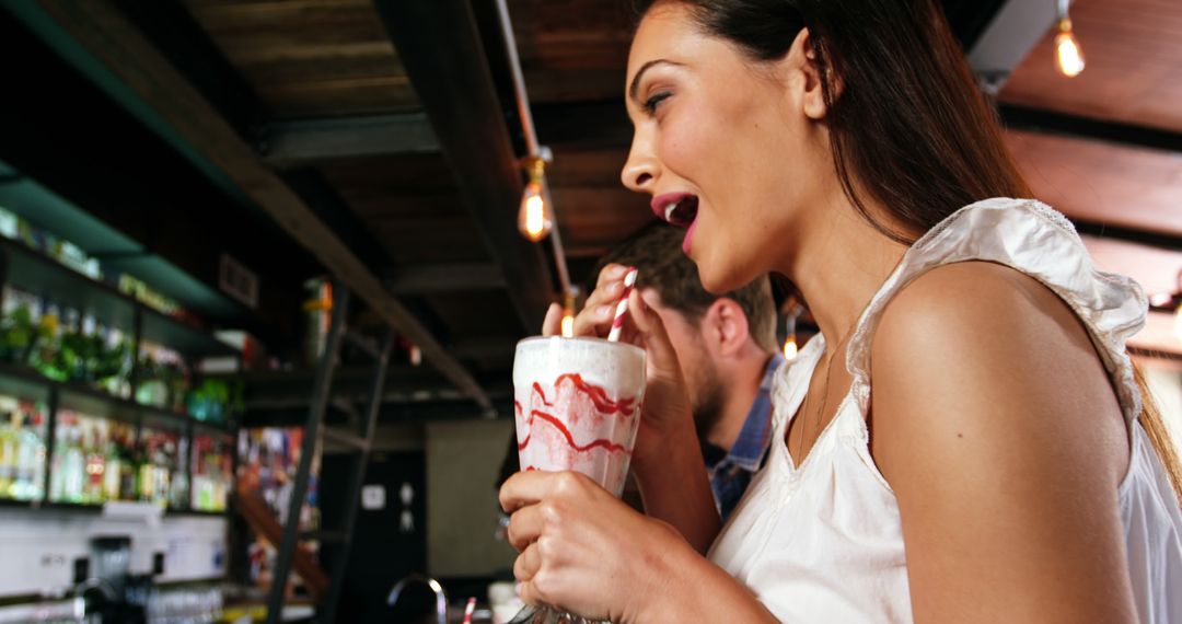 Woman Enjoying Milkshake at Busy Bar with Friend at Night - Free Images, Stock Photos and Pictures on Pikwizard.com