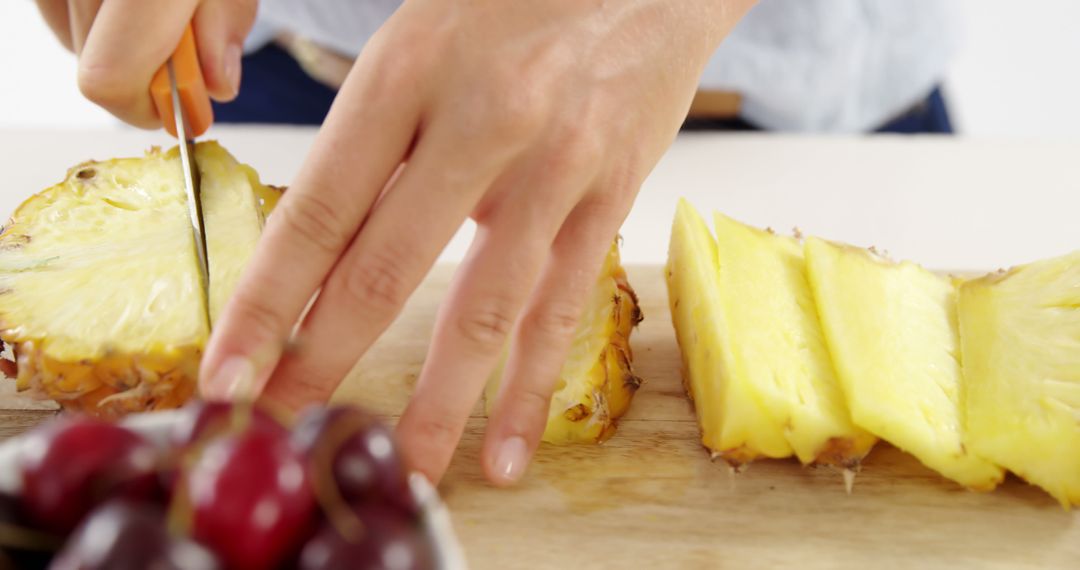 Hands Slicing Fresh Pineapple with Bowl of Cherries - Free Images, Stock Photos and Pictures on Pikwizard.com