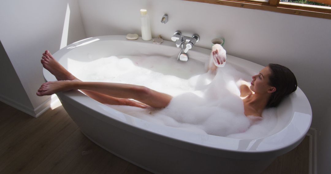 Relaxed Woman Enjoying Bubble Bath in White Bathtub - Free Images, Stock Photos and Pictures on Pikwizard.com