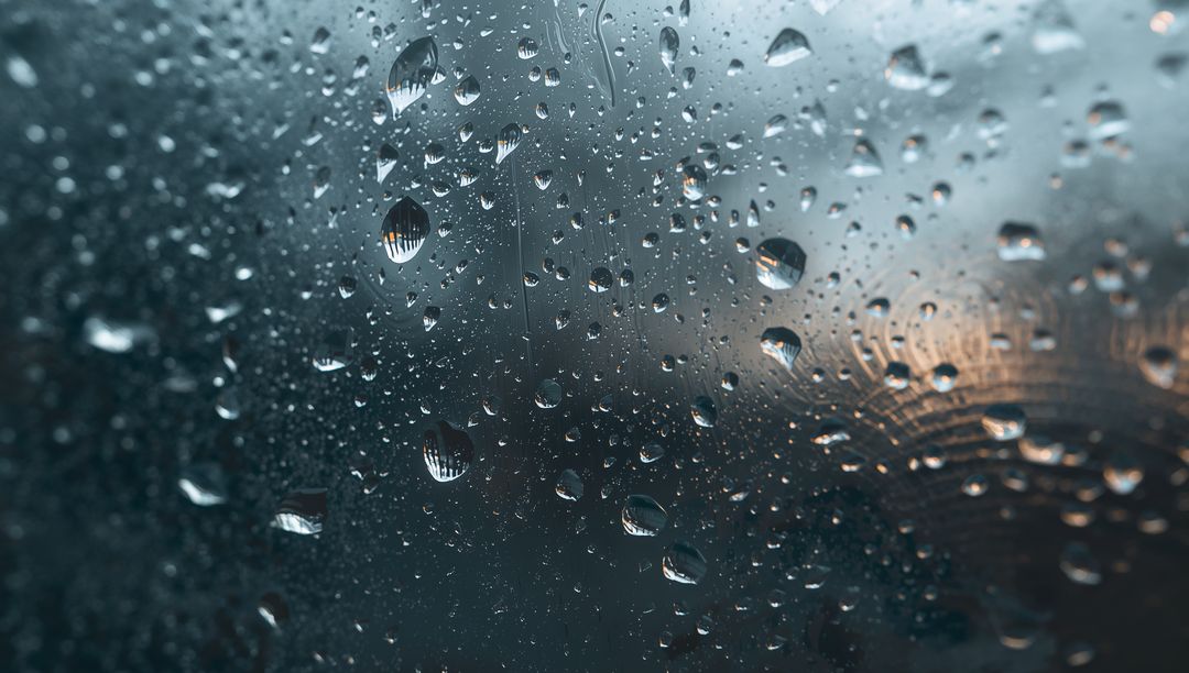Moody Raindrops Clinging to Window Glass with Warm Bokeh Reflections