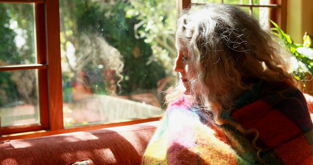 Woman Wrapped in Blanket Sitting by Window on Sunny Day - Free Images, Stock Photos and Pictures on Pikwizard.com