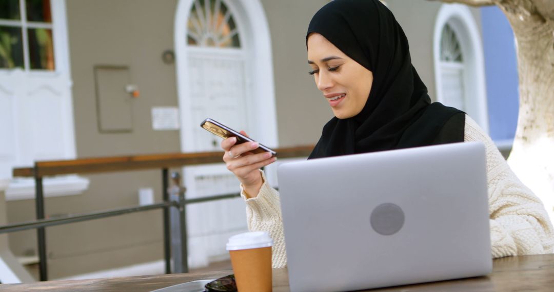 Young Muslim Woman Using Smartphone at Outdoor Cafe - Free Images, Stock Photos and Pictures on Pikwizard.com