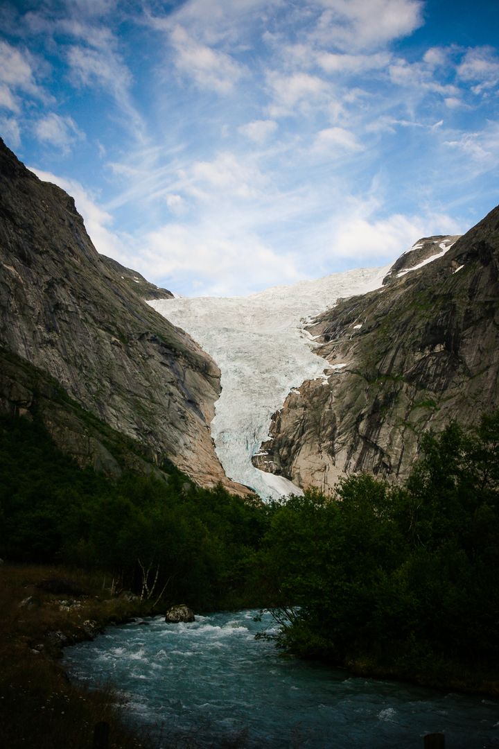 Majestic Glacier Flowing Between Steep Mountain Cliffs and Turquoise River - Free Images, Stock Photos and Pictures on Pikwizard.com