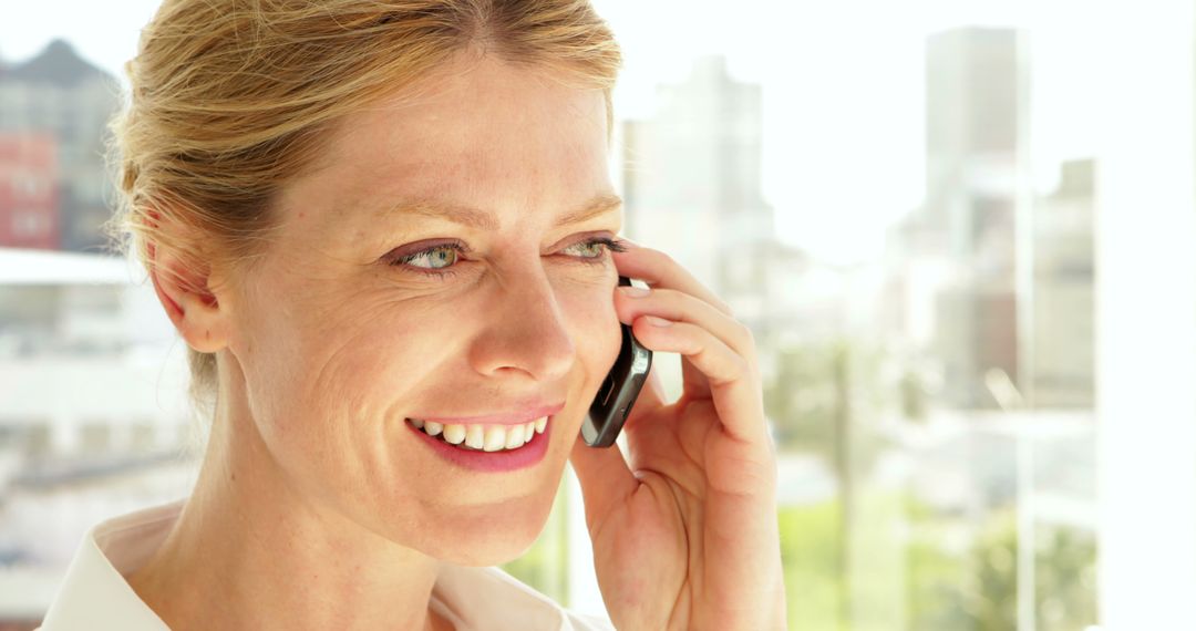 Businesswoman Smiling While Talking On Phone In Bright Office - Free Images, Stock Photos and Pictures on Pikwizard.com