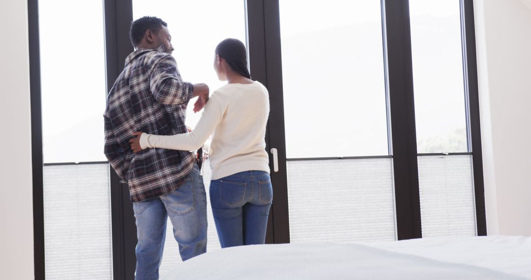 Couple Embracing While Looking Out Large Window at Home