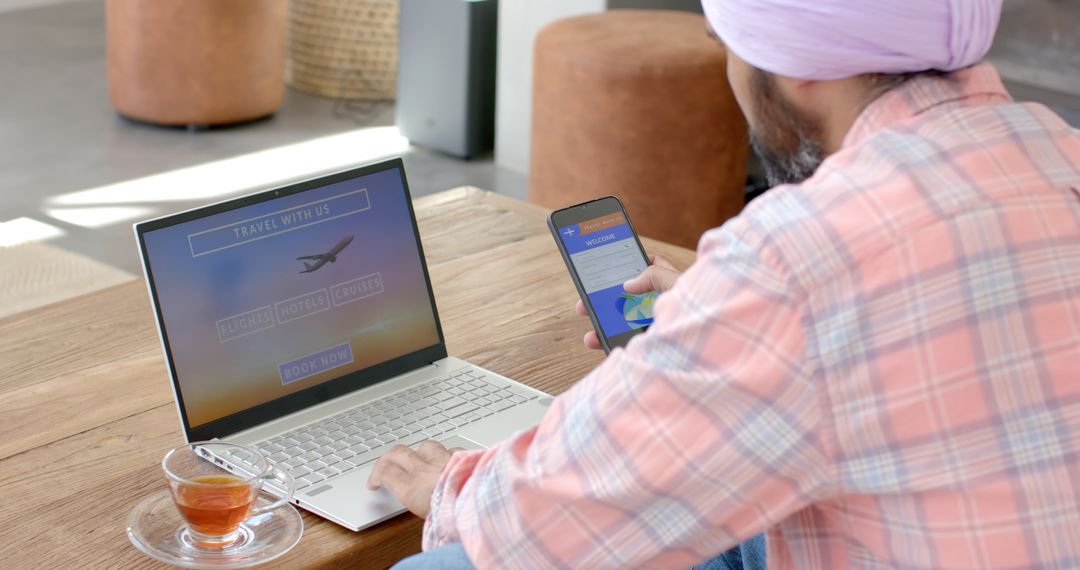 Man Booking Travel Online at Home with Laptop and Smartphone