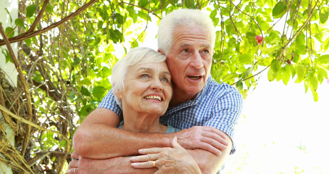 Senior Couple Embracing Outdoors Under Lush Greenery - Free Images, Stock Photos and Pictures on Pikwizard.com