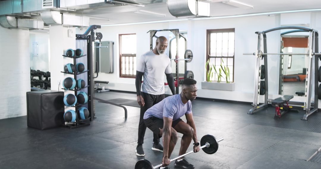 Trainer Guiding Client in Lifting Barbell for Strength Training