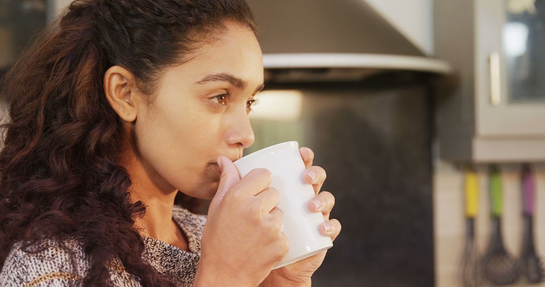 Young Woman Drinking Hot Beverage in Kitchen - Free Images, Stock Photos and Pictures on Pikwizard.com