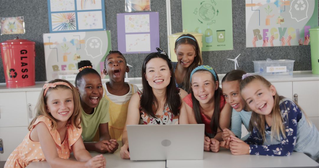 Diverse Teacher with Enthusiastic Students Using Laptop in Classroom