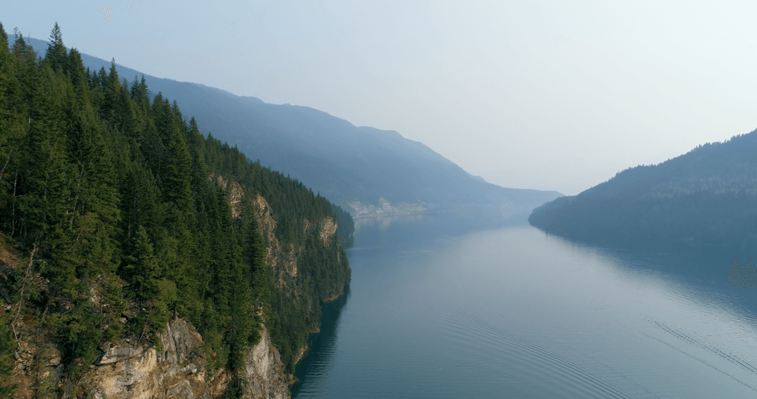 Tranquil River with Misty Mountains and Lush Greenery in Daylight