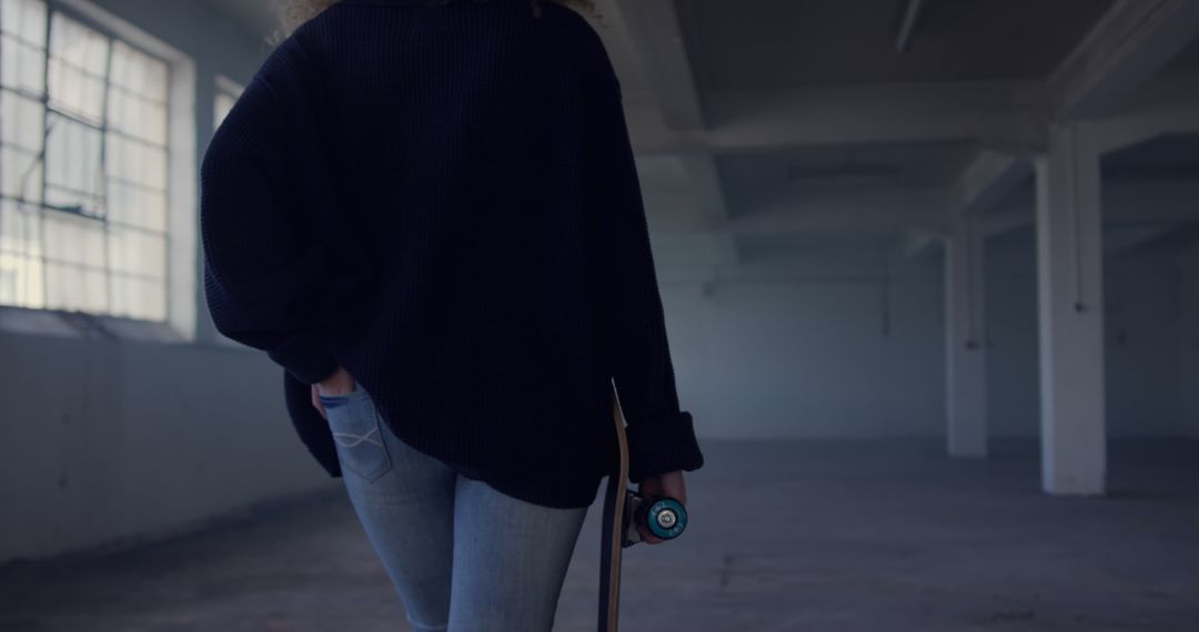 Girl Holding Skateboard in Industrial Building - Free Images, Stock Photos and Pictures on Pikwizard.com