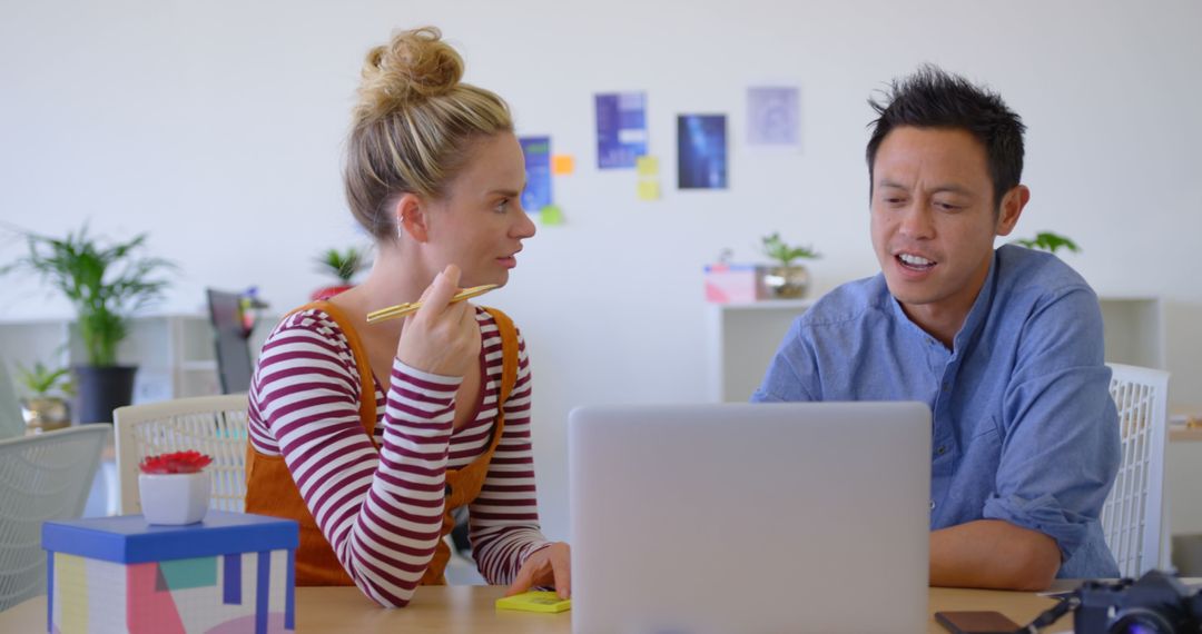 Diverse Colleagues Collaborating on Laptop in Innovative Workspace