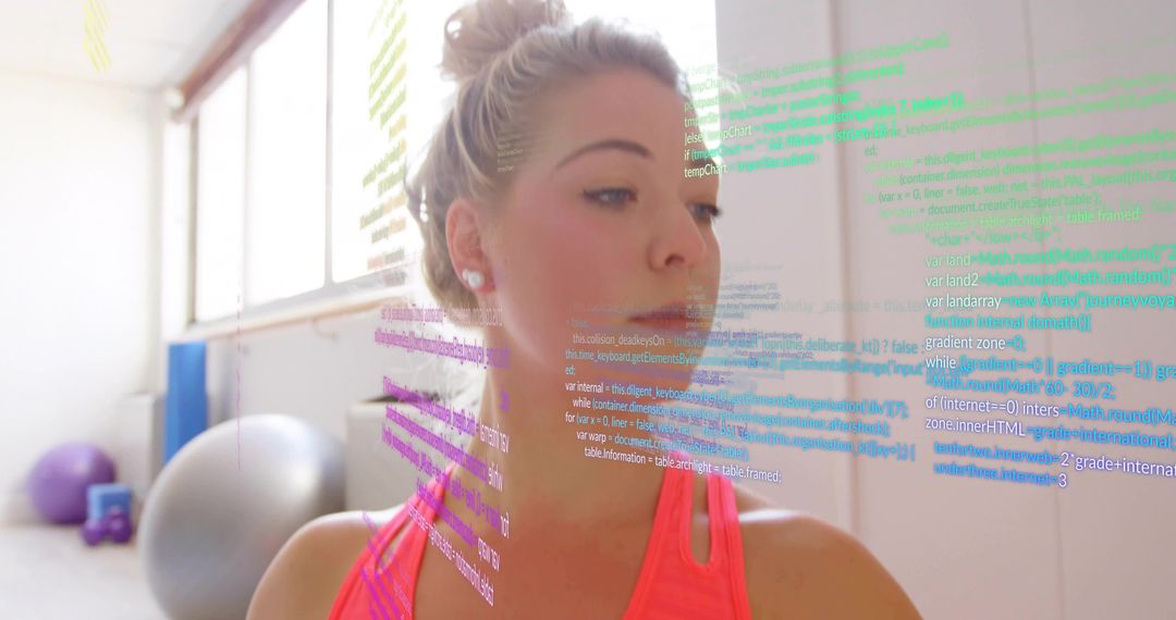 Turning woman in coral tank top with augmented code overlay in bright gym studio