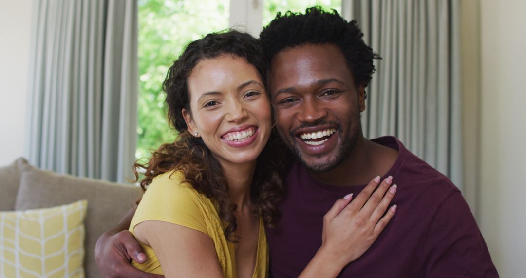 Happy Biracial Couple Embracing and Smiling Together at Home