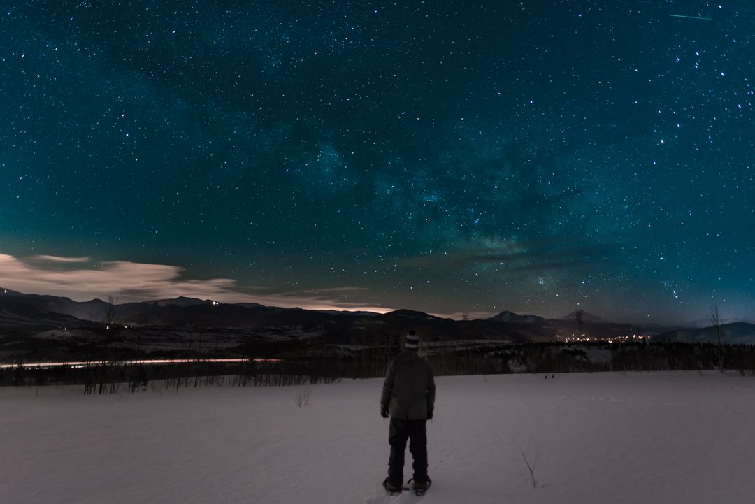 Person Stargazing in Snowy Landscape Under Star-filled Sky at Night - Free Images, Stock Photos and Pictures on Pikwizard.com