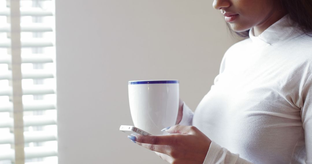 Woman using mobile phone while having cup of coffee at home - Free Images, Stock Photos and Pictures on Pikwizard.com