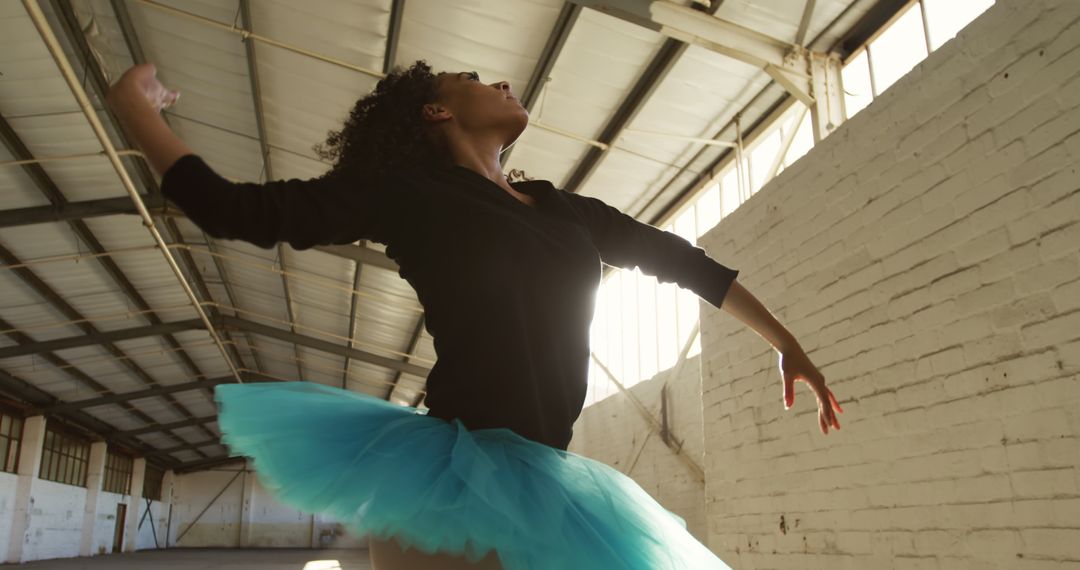 Dedicated ballerina dancing gracefully in sunlit warehouse - Free Images, Stock Photos and Pictures on Pikwizard.com