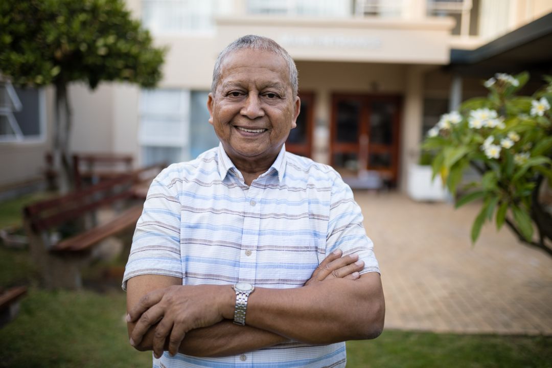 Smiling Senior Man Standing with Arms Crossed in Front Yard